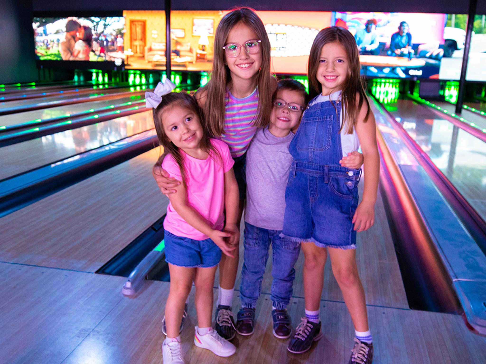 kids smiling in front of bowling alley
